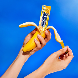 A hand unpeeling Hi-CHEW Banana Stick