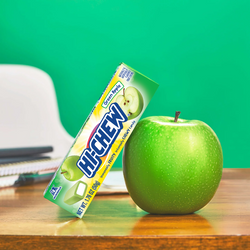 Hi-Chew Green apple stick leaning on a green apple